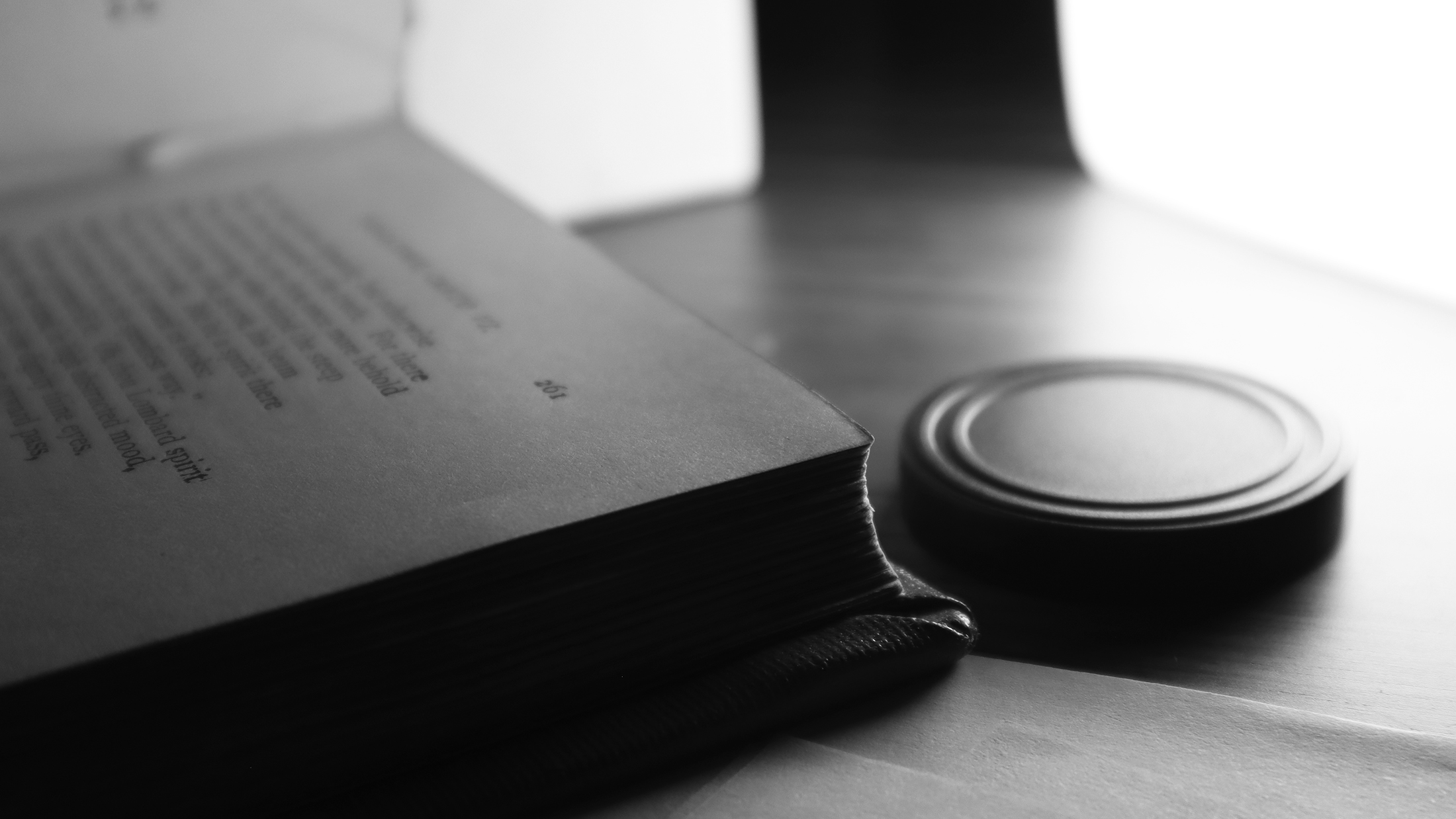 Photograph of an open spread of Dante's Inferno on a table, at an angle surrounded by light.