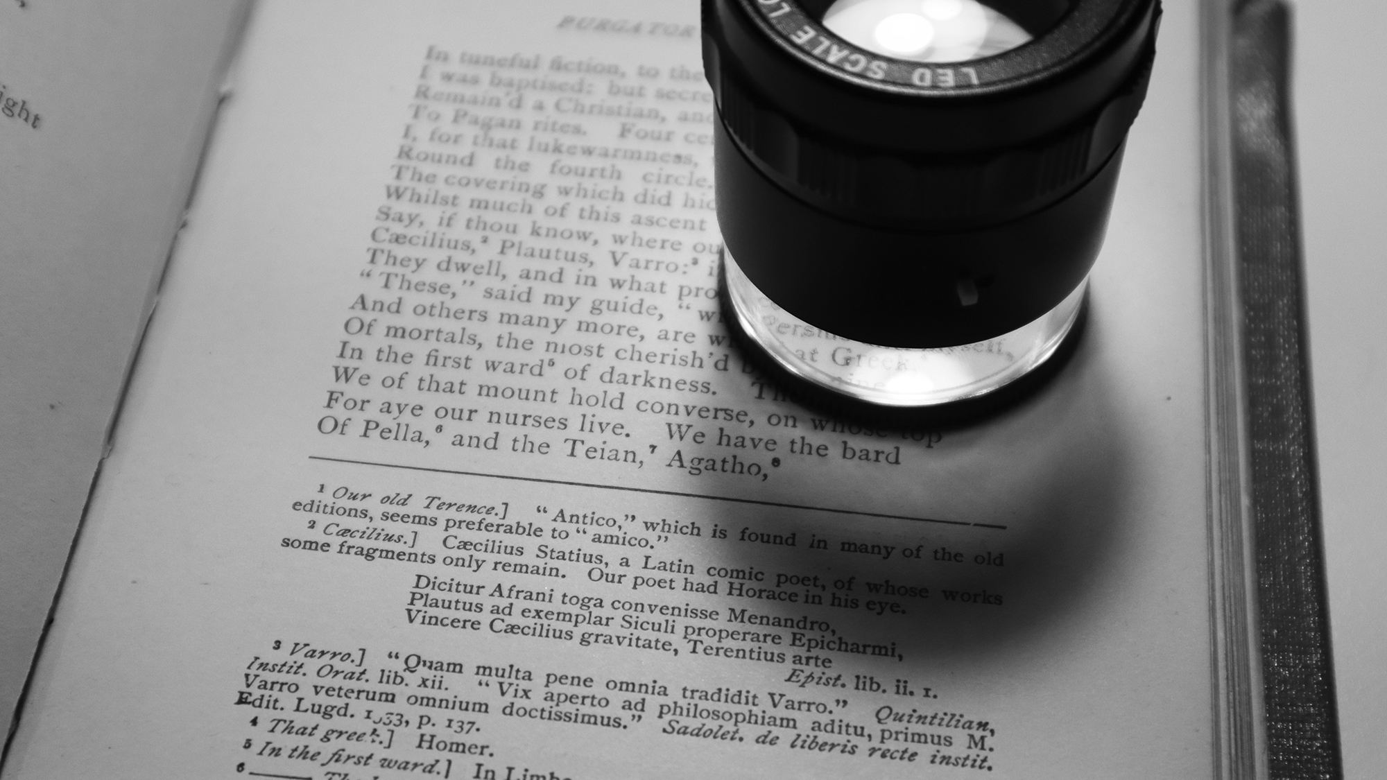 Photograph of a 10x micro lens / loupe on top of a page of Dante's Pergatory.