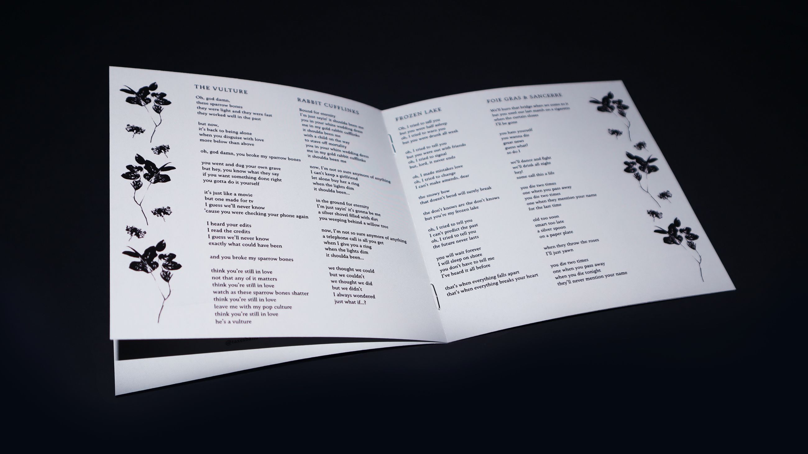 Close-up shot of just the booklet, opened, with the lyrics printed towards the center and flower pattterns on the edges